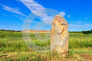 View of the ancient kurgan stela, stone idol against the backdrop of ancient mound of sandstone boulders
