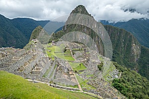 View of the ancient mountains of Machu Picchu and part of the city ruins, under a cloudy sky