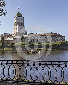 View of ancient Vyborg castle with embankment fence in summer. Russia