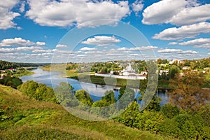 View on ancient white-stone Convent of the Dormition built in 16 century on Volga River bank with reflection in water. Staritsa,
