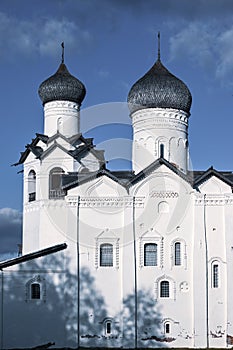 View of the ancient white-stone Monastery with wooden domes, white facade, windows, platbands in the city of Staraya Russa.