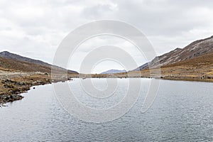 View of another perspective of Laguna Tecllo with some hills and rocks in the morning in Shupluy