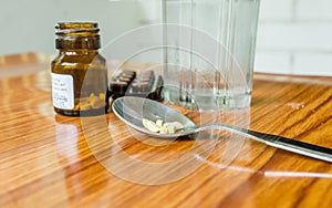 View of antioxidants vitamin tablet, pill blisters, a bottle of drug, capsule in measuring spoon, with glass of water placed on