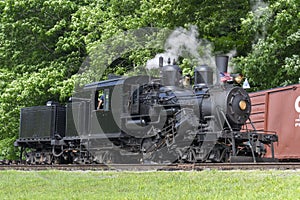 View of a Antique Shay Steam Engine Moving Slowly Blowing Smoke and Steam on a Sunny Day photo