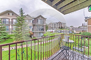 View of an apartment buildings with lawn at the front and vehicles on a parking lot