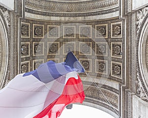 View of Arc de Triomp with flag of France waving in wind on Place de Gaulle in Paris, France