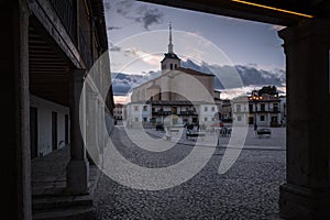 View of the arcaded square of Colmenar de Oreja with the Church of Santa Maria in the background at sunset, Spain photo