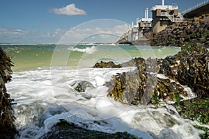 View on the architecture of the flood barrier `Neeltje jans` in the Netherlands from the rocky coast with seaweed and splashing photo