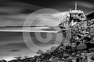 View on the architecture of the flood barrier `Neeltje jans` in the Netherlands from the rocky coast with seaweed and splashing photo