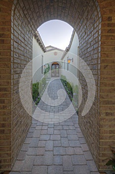 View through archway down path to French doors of luxury home