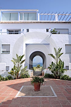 View through archway to sunny lawn garden and sea