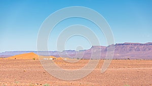 View of an arid landscape in the desert with a village and brown mountains in the background