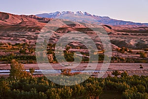 View of Asif Ounila river with desert and snow covered Atlas mountains in the background