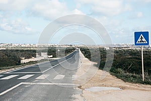 View of the asphalt road and pedestrian crossing and road sign.