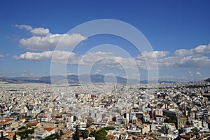 View of Athens cityscape showing lowrise white buildings architecture, mountain, trees, white cloud and blue sky background