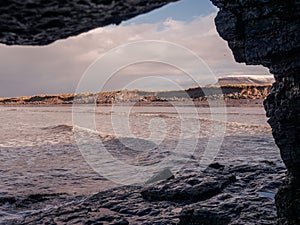 View on Atlantic ocean from a cave by Rosses point beach in county Sligo Ireland, Benbulben mountain covered with snow on the