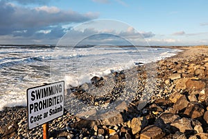 View on Atlantic ocean, Strandhill beach, county Sligo Ireland. Swimming prohibited sign in English and Irish language, Cloudy sky