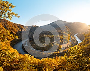 View of autumn scenery of Domasinsky meander illuminated with sunset light in Zilina region, Slovakia. The Vah River flows past