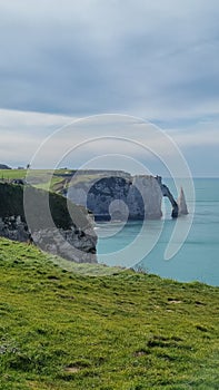 View of the Aval cliff with the arch and the Needle seen from the pebble beach of Etretat in Normandy on a sunny spring morning