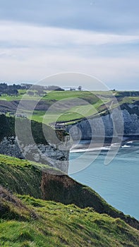 View of the Aval cliff with the arch and the Needle seen from the pebble beach of Etretat in Normandy on a sunny spring morning