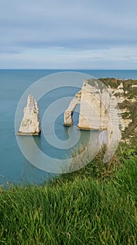 View of the Aval cliff with the arch and the Needle seen from the pebble beach of Etretat in Normandy on a sunny spring morning