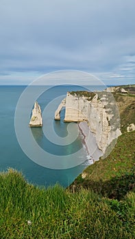 View of the Aval cliff with the arch and the Needle seen from the pebble beach of Etretat in Normandy on a sunny spring morning