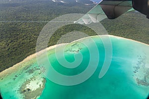 View of wing, azure lagoon and yellow sandy beach from an airplane window, Isle of Pines, New Caledonia. Oceania.