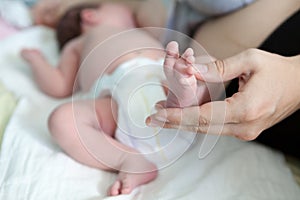 View at baby foot in mother hand, infant lying on bed during breast-feeding