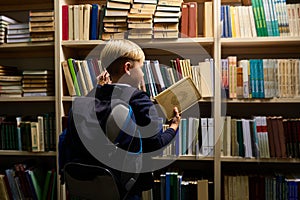 view from back on awesome child boy choosing book in library