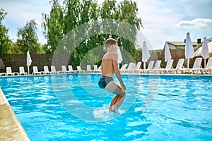 View back of boy jumping into pool