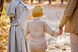 View from back on family with child boy walking having fun in forest on autumn season