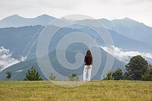 A view from the back of a girl on a mountain and admires the beautiful view. Beautiful mountain view. Travel concept