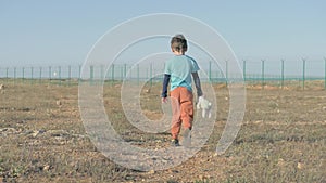 View from the back of juvenile child leaving moving towards Mexican border. Unhappy Abandoned Lonely boy walk with her Friend Tedd