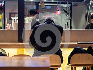 View from the back of a man sitting at the bar in a fast food restaurant. Business lunch during the lunch break