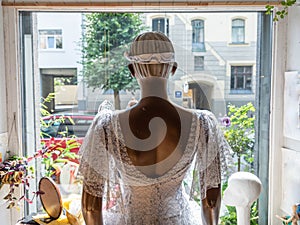 View from the back of the mannequin in beautiful white lace dress at the window.