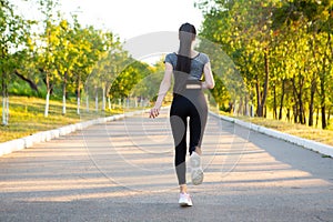 View on back of running woman athlete in the park.