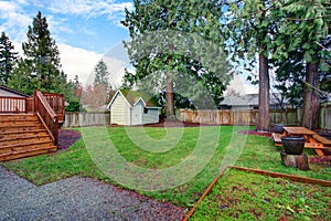 View of a back yard with green grass and small shed.