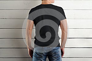 View from the back young man in a black T-shirt on a white wooden background.