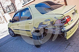 View of a badly crashed yellow car parked on the street captured on a sunny day