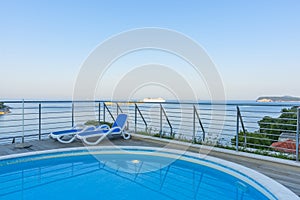 View from balcony across pool and Mediterranean Sea as cruise ship passes small off-shore islands in distance off Croatian coast