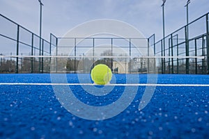 view of a ball on the baseline of a blue paddle tennis court, racket sport concept