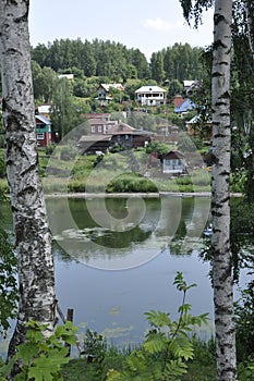 The view from the banks of the river to the mountain in small village houses through Russian white birch .