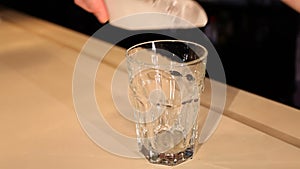 View of barman puts ice cubes in cocktail glass