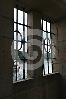 View through a barred window at the Staudam on the Eder lake with a ship