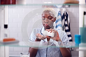 View Through Bathroom Cabinet Of Young Woman Taking Medication From Container