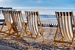 View of beach chairs on a sandy beach, with a serene blue ocean in the background