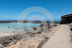 View of a beach with emerald water and dark volcanic rocks in Lobos island Canary islands