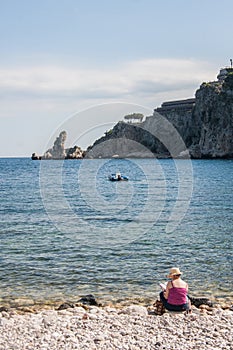 Woman reading a book on the beach near Giardini - Naxos, Sicily, Italy