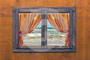 View of beach through a wooden window with golden curtains