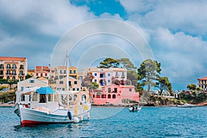 View of beautiful bay of Assos village with fishing boat at anchor in front and clouds in background, Kefalonia island